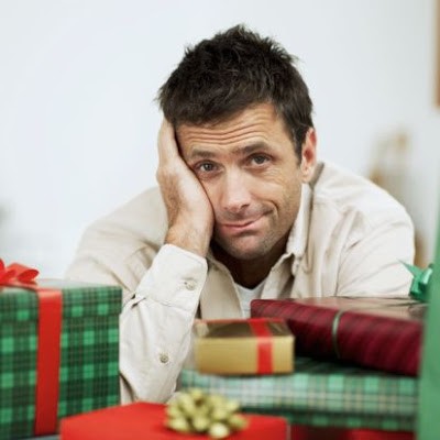 mid adult man sitting confused amidst a pile of wrapped gifts